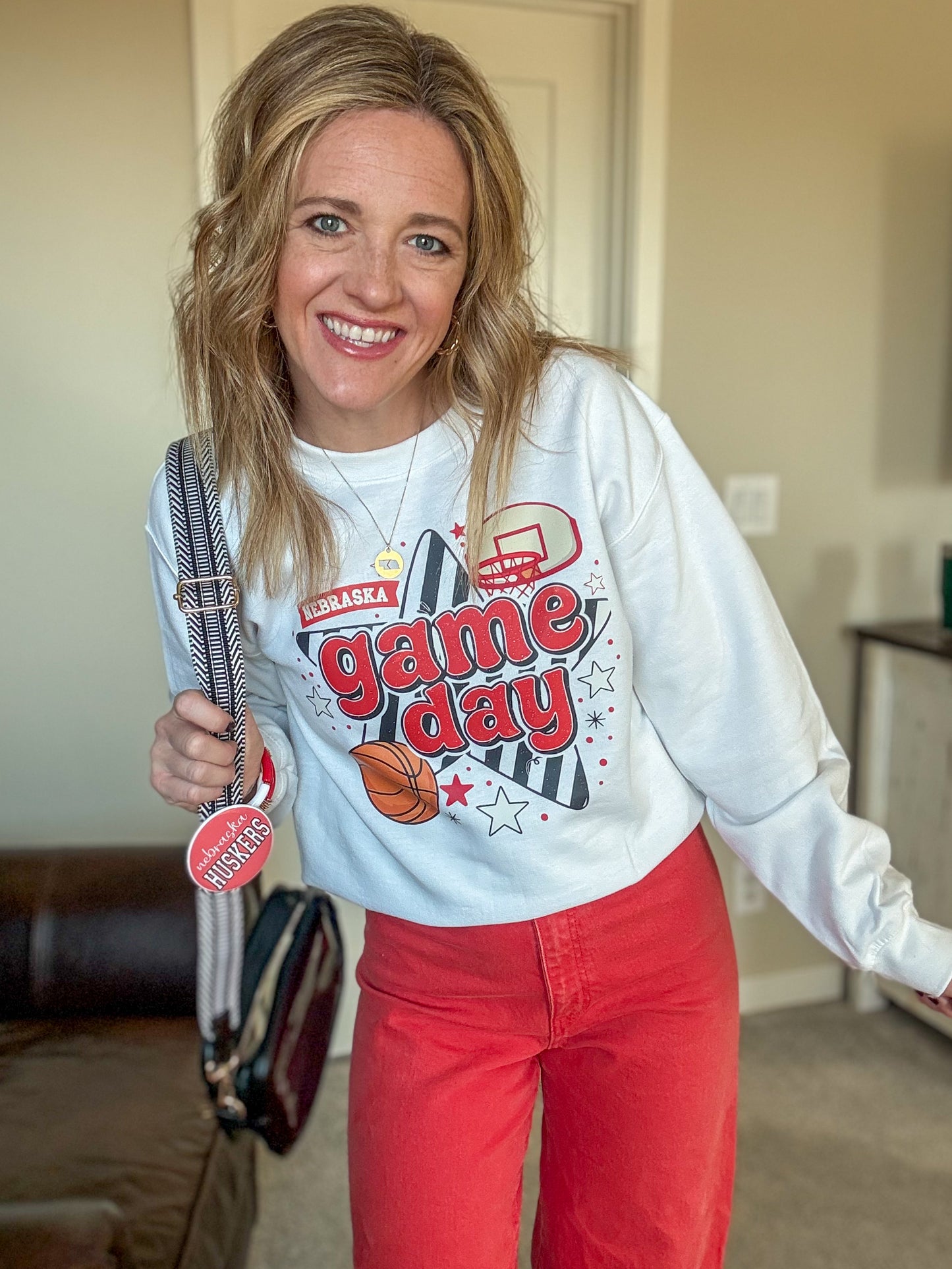 Woman wearing a 'game day' sweatshirt with a graphic design, standing indoors.