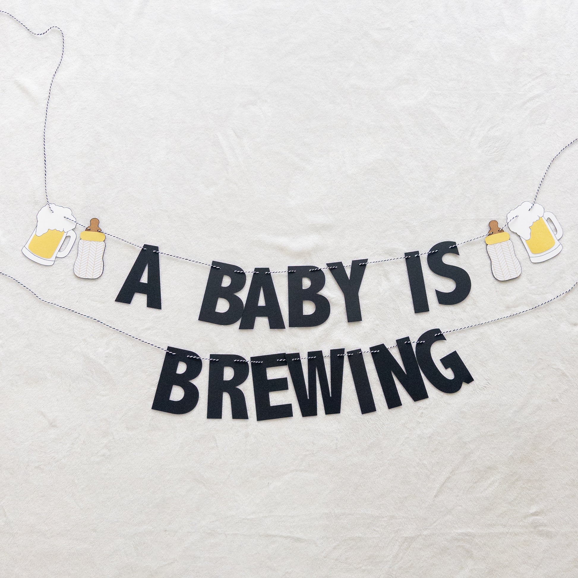 Decorative banner with 'A Baby is Brewing' text in black cardstock
