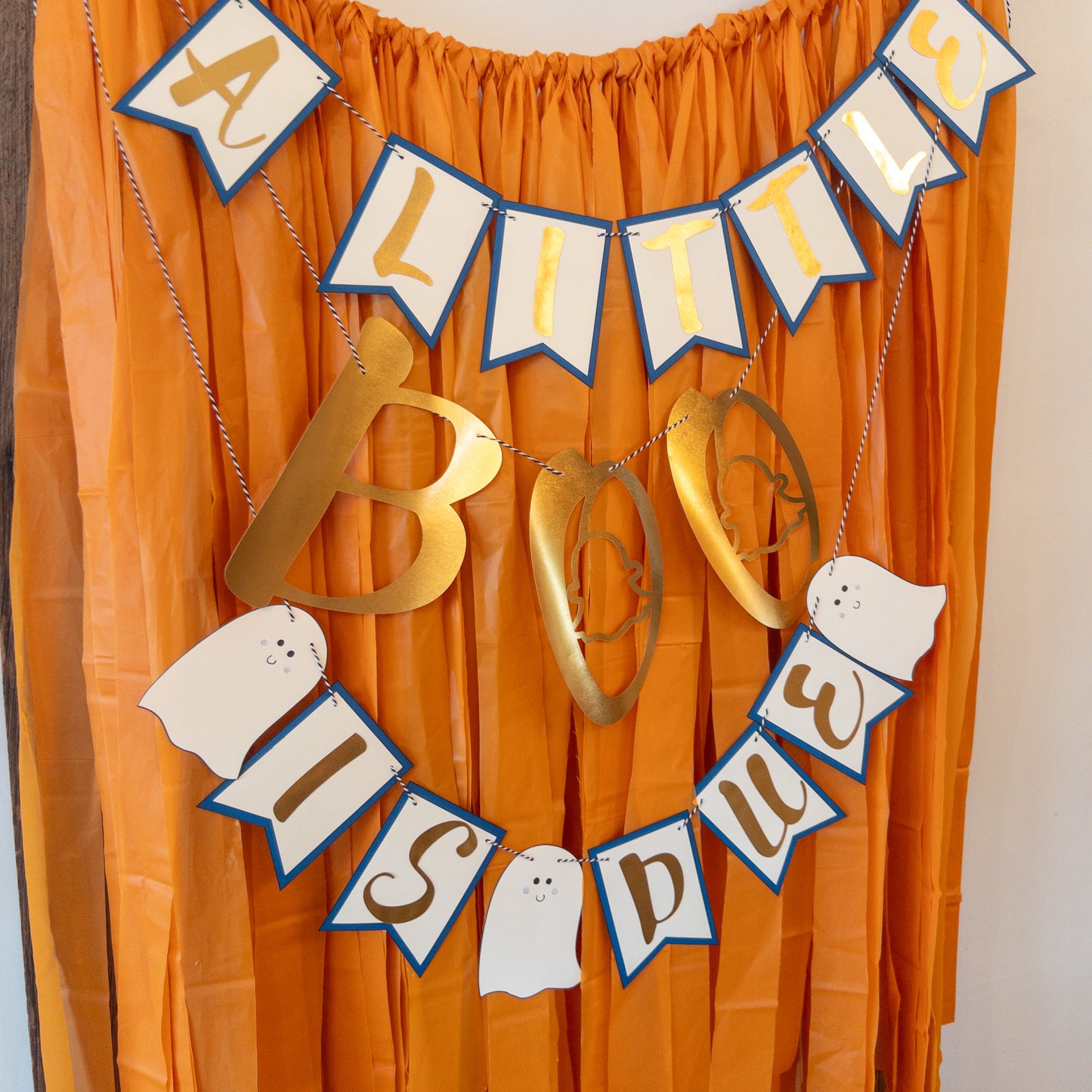 A decorative banner with the text 'A LITTLE BOO IS DUE' in a Halloween-themed design, featuring ghost shapes and gold letters on a string.