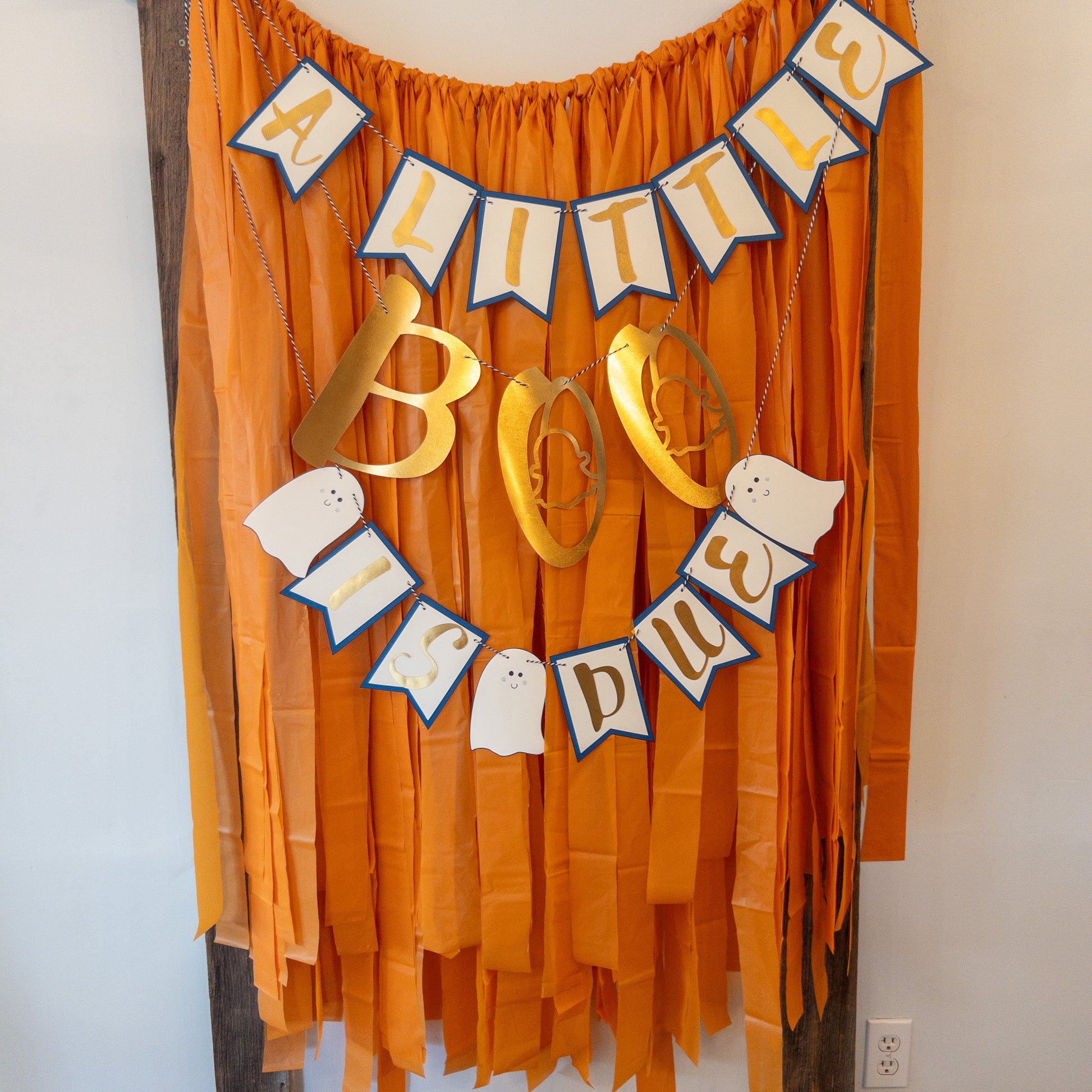 A decorative banner with the text 'A LITTLE BOO IS DUE' in a Halloween-themed design, featuring ghost shapes and gold letters on a string.