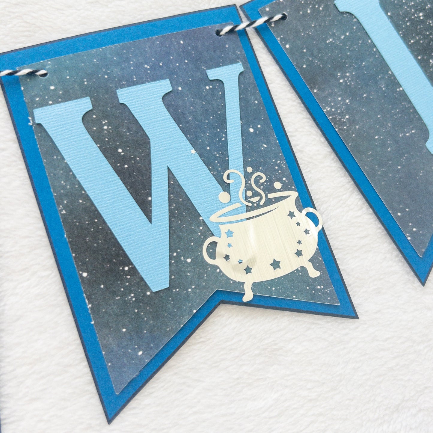 A banner with blue paper letters spelling 'A BABY IS BREWING' with stars and a blue border