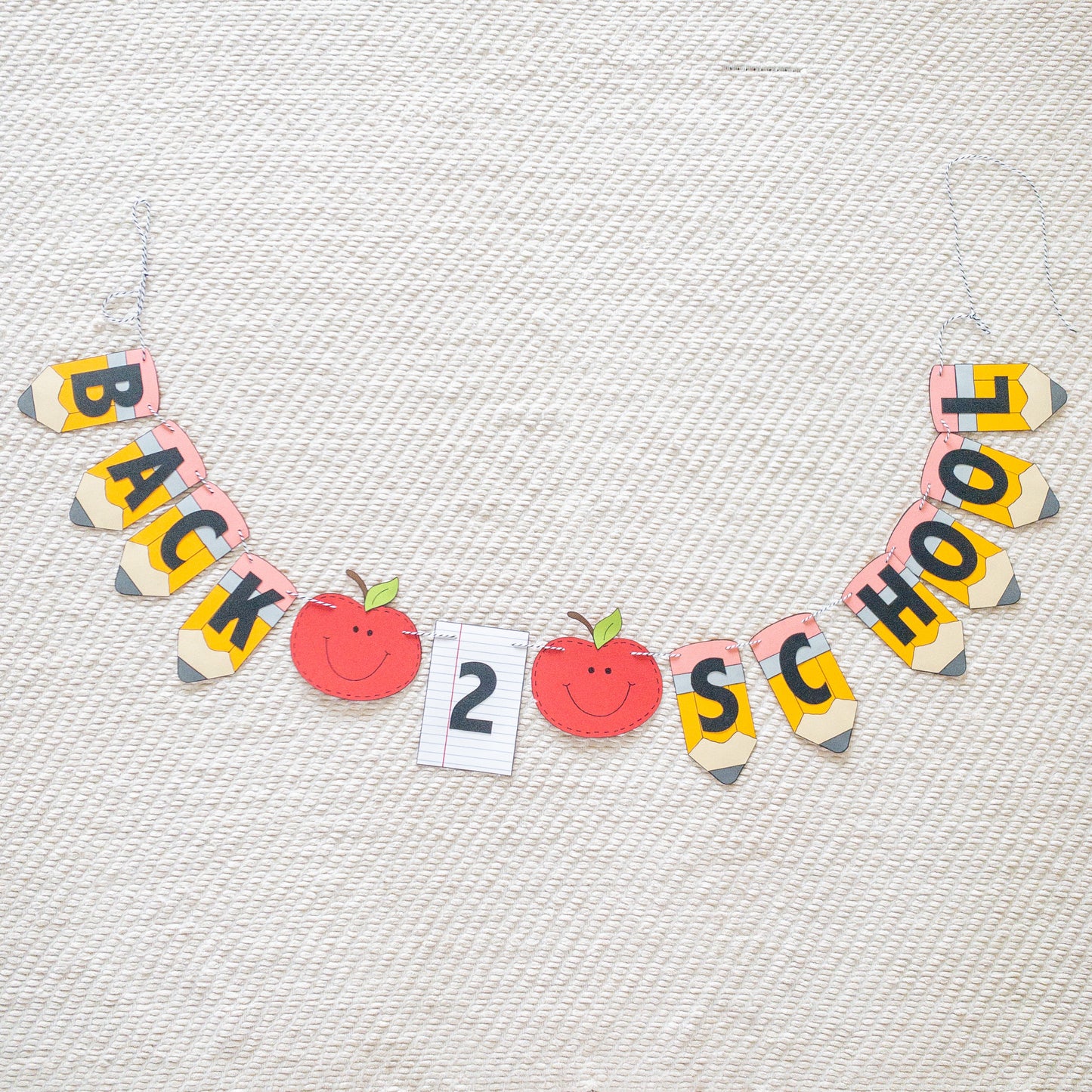 A 'Back to School' themed banner made of paper letters spelling out the phrase, with decorative elements such as apples and pencils, and a piece of lined paper.