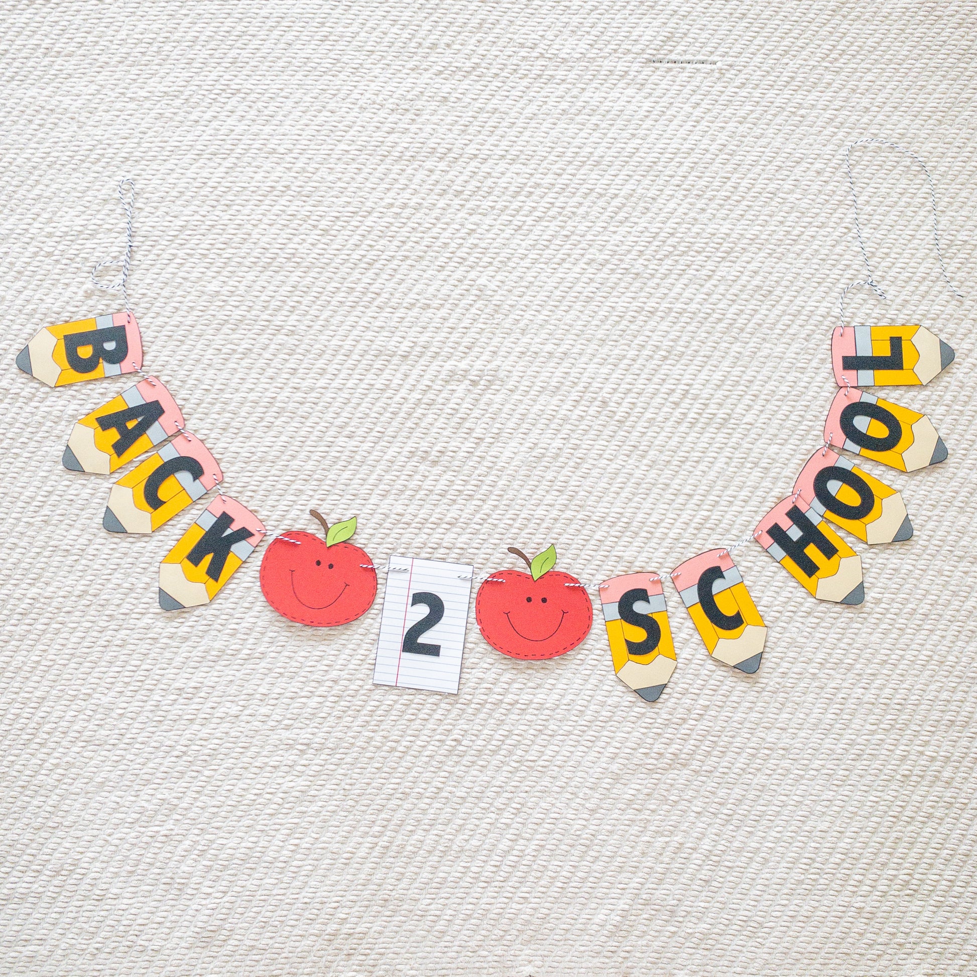 A 'Back to School' themed banner made of paper letters spelling out the phrase, with decorative elements such as apples and pencils, and a piece of lined paper.