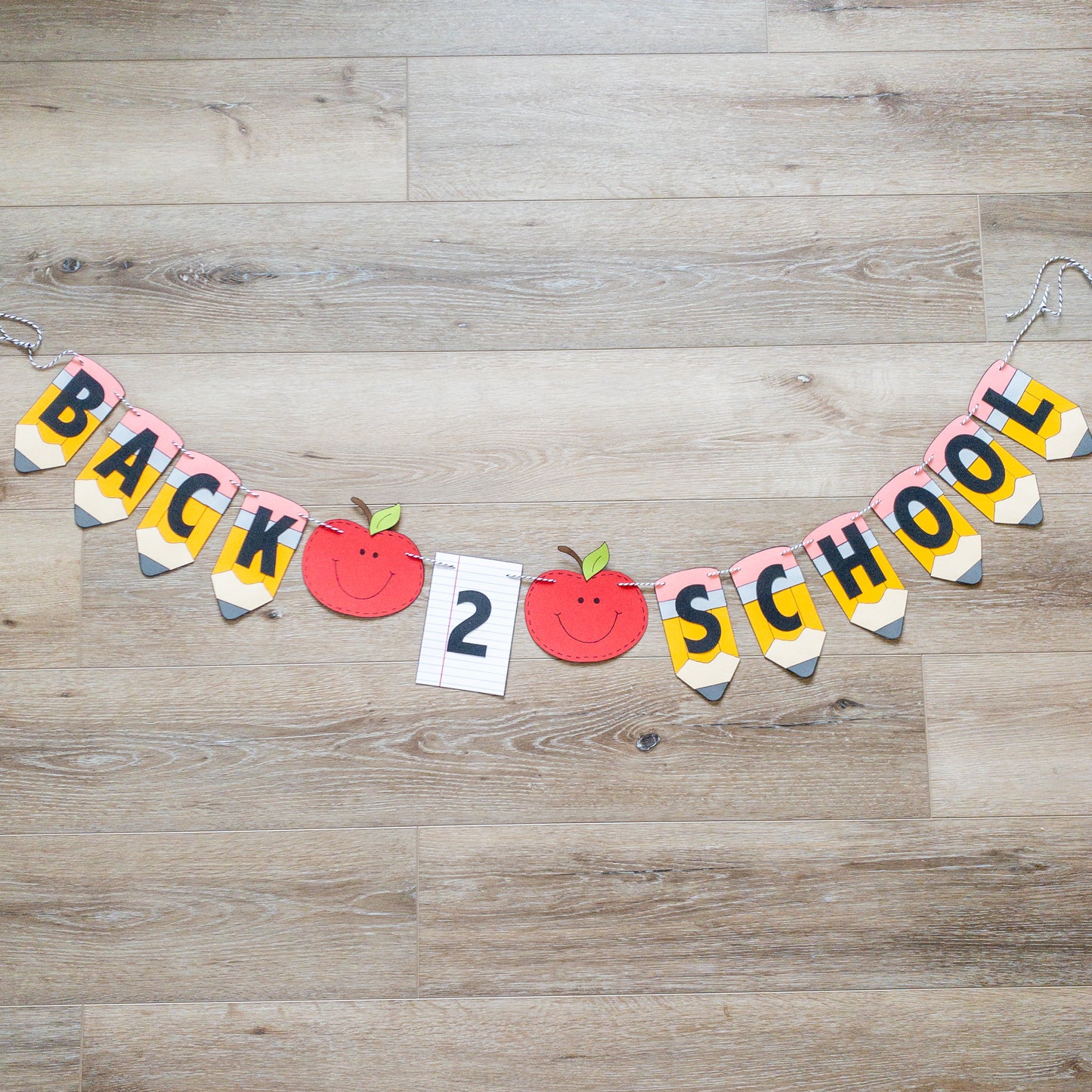 A 'Back to School' themed banner made of paper letters spelling out the phrase, with decorative elements such as apples and pencils, and a piece of lined paper.