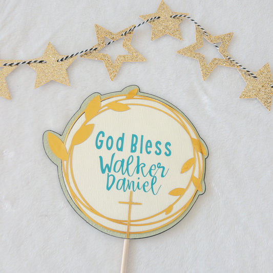 A cake topper with a gold background, teal text, and decorative stars, designed for a baptism or christening celebration.