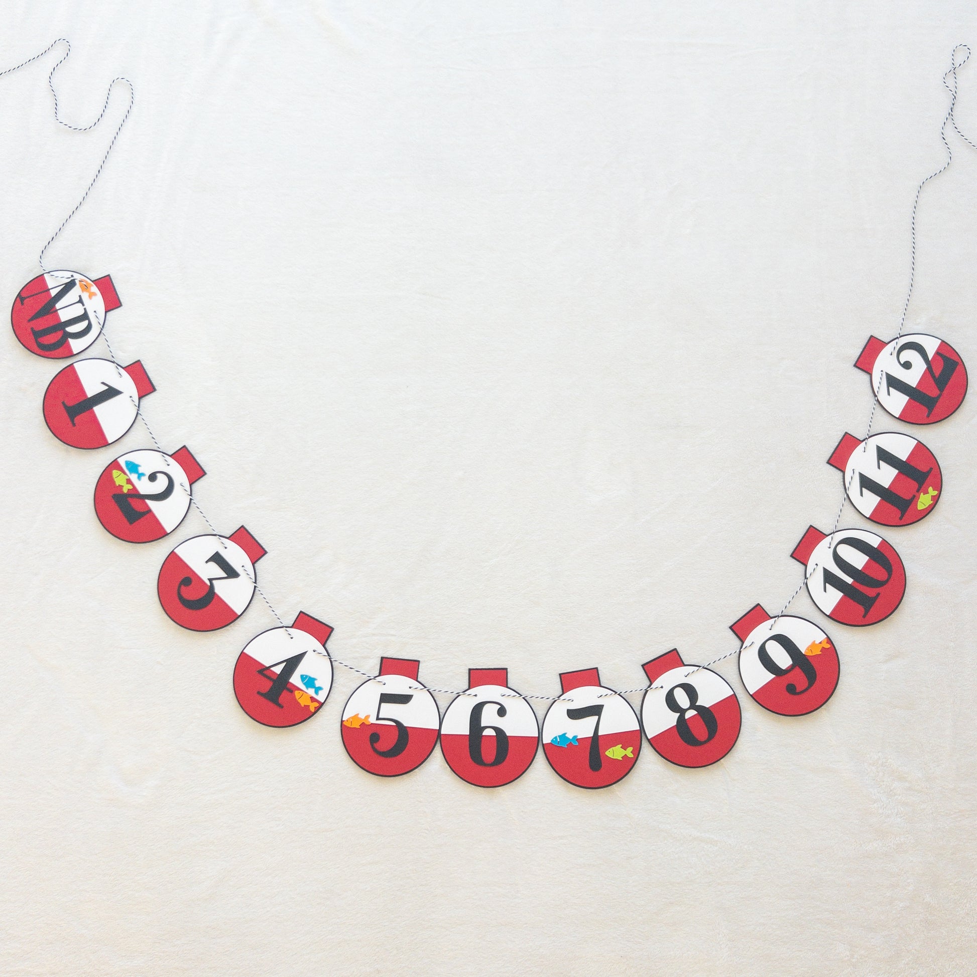 A custom banner featuring a series of round, red and white paper fishing bobbers with numbers representing months, strung on a string.