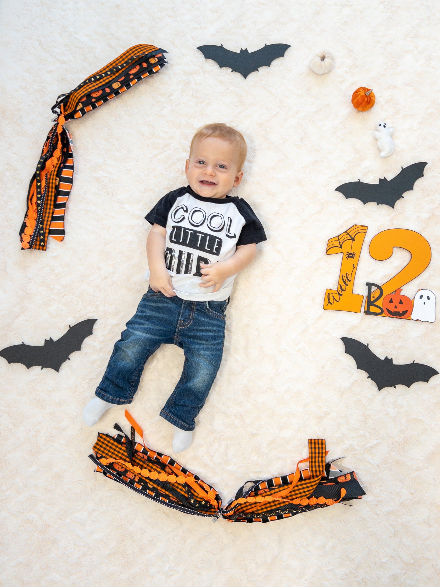 A bay laying next to Halloween decor with a number showing how many months he is 