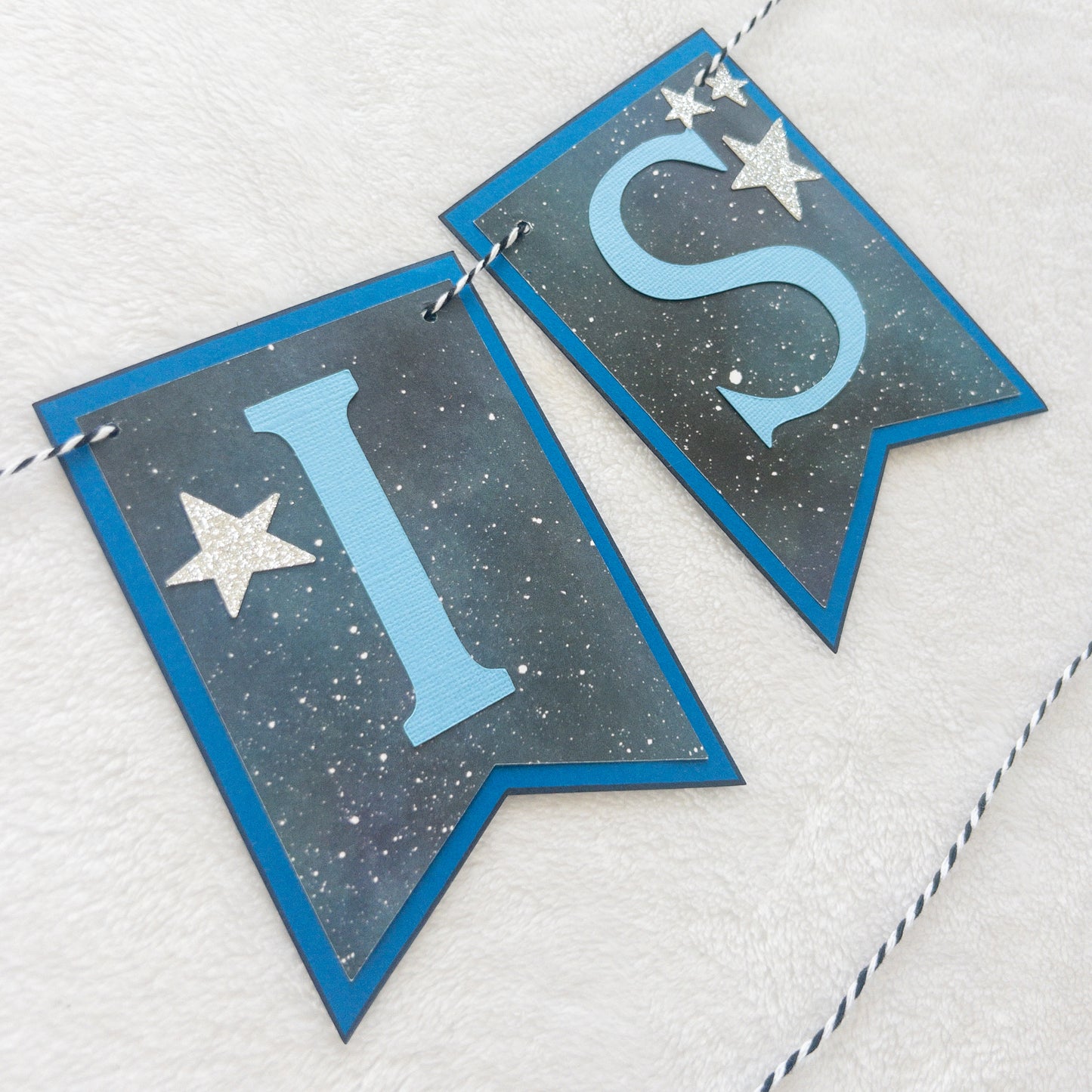 A banner with blue paper letters spelling 'A BABY IS BREWING' with stars and a blue border