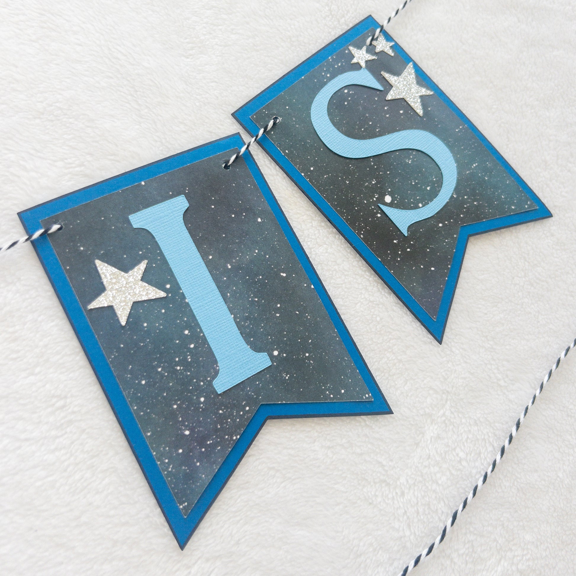 A banner with blue paper letters spelling 'A BABY IS BREWING' with stars and a blue border