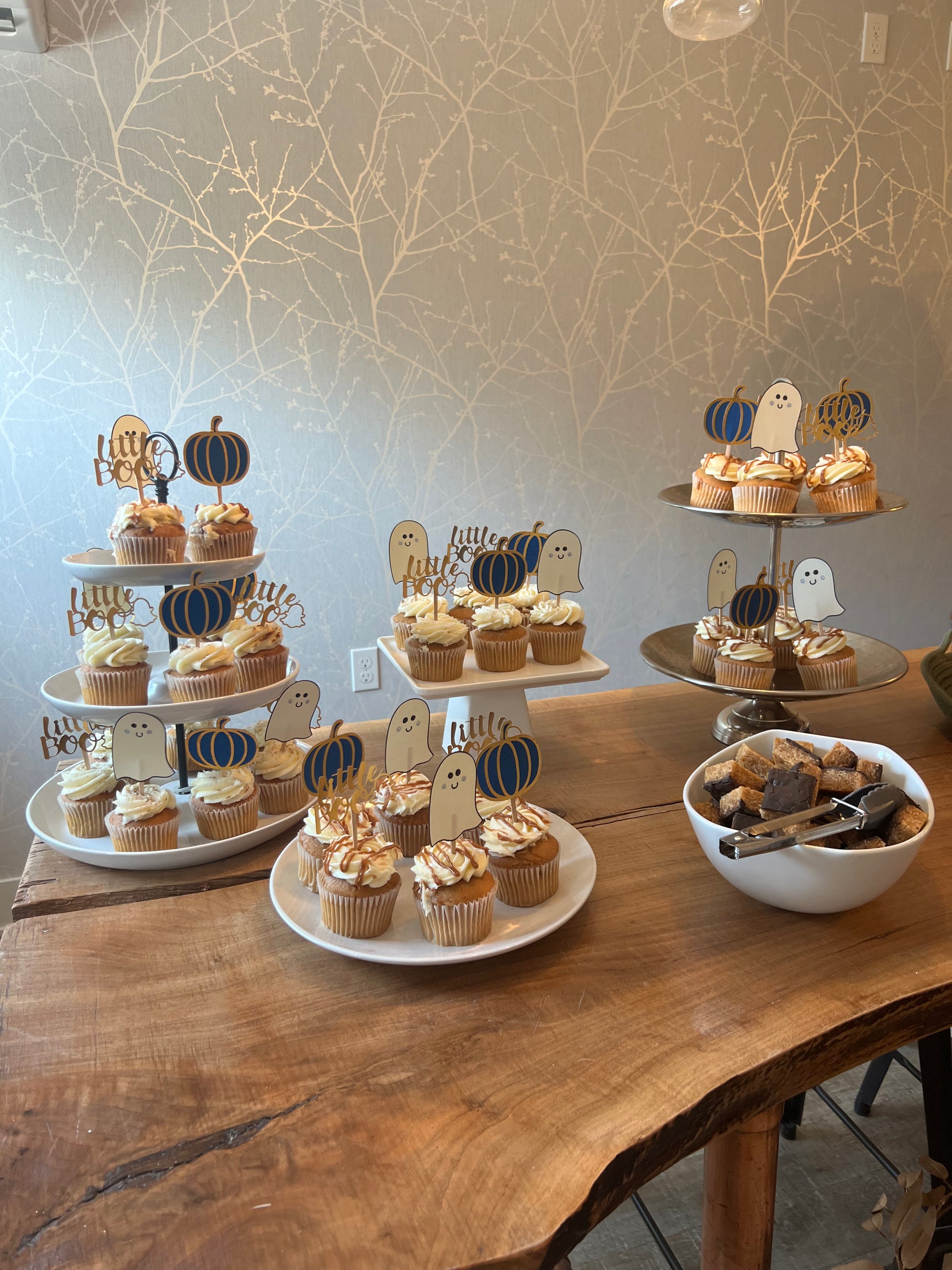 Cupcake toppers with wooden sticks, one designed as a ghost, 'Little Boo' text, and the other shaped like a pumpkin