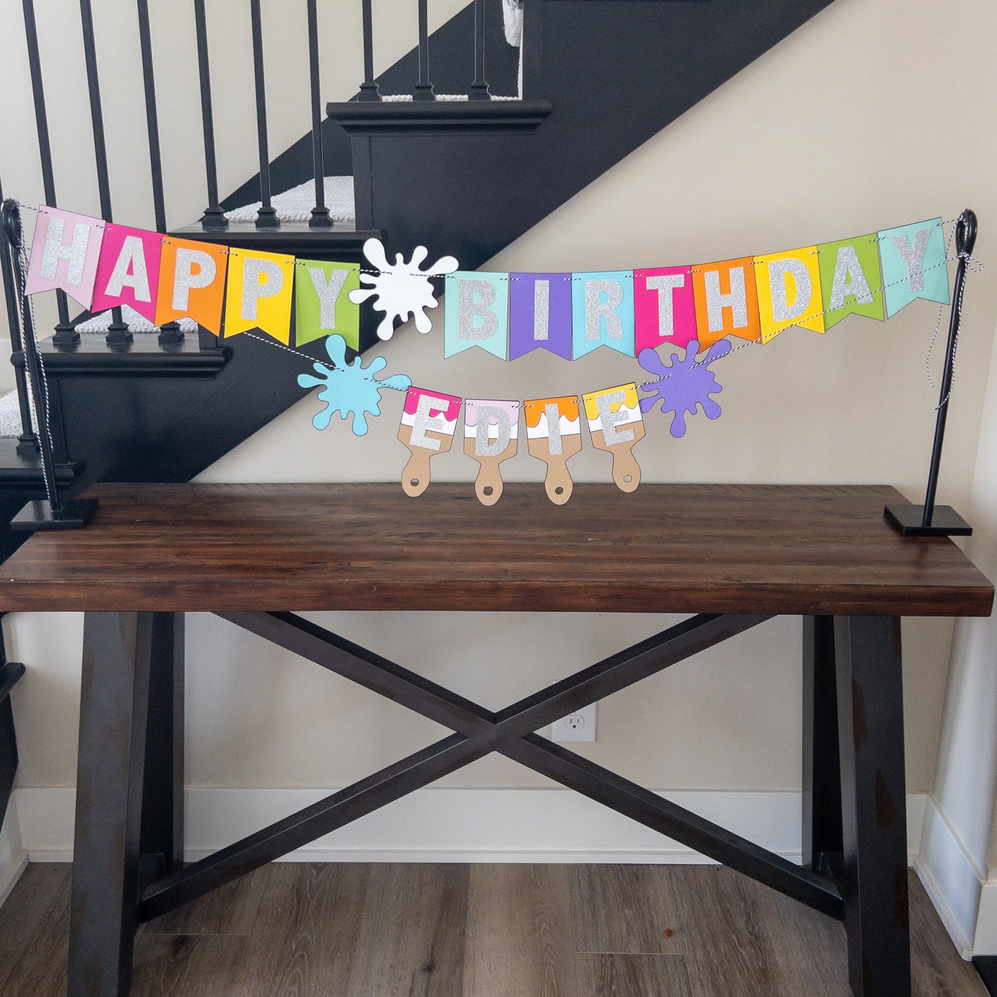 Features the words ‘happy birthday’ in bright and colorful paper. Includes the birthday girl’s name on paint brushes. The letters are made of kit sparkly silver. There are paint splatters on each side of the name.