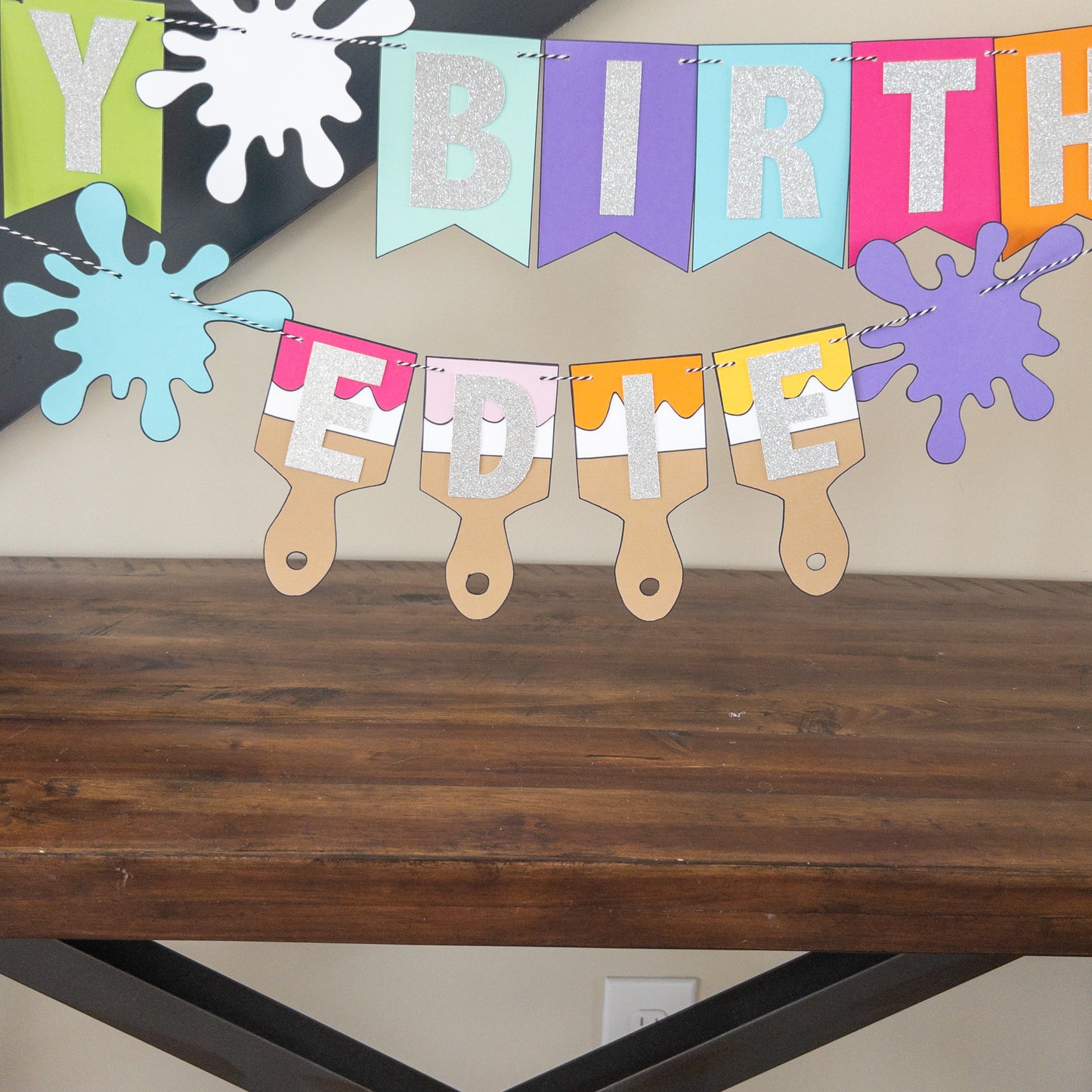 Features the words ‘happy birthday’ in bright and colorful paper. Includes the birthday girl’s name on paint brushes. The letters are made of kit sparkly silver. There are paint splatters on each side of the name.