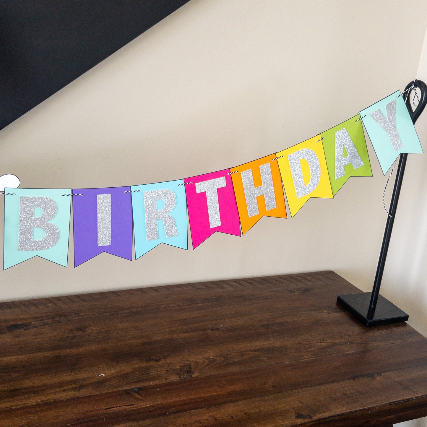 Features the words ‘happy birthday’ in bright and colorful paper. Includes the birthday girl’s name on paint brushes. The letters are made of kit sparkly silver. There are paint splatters on each side of the name.