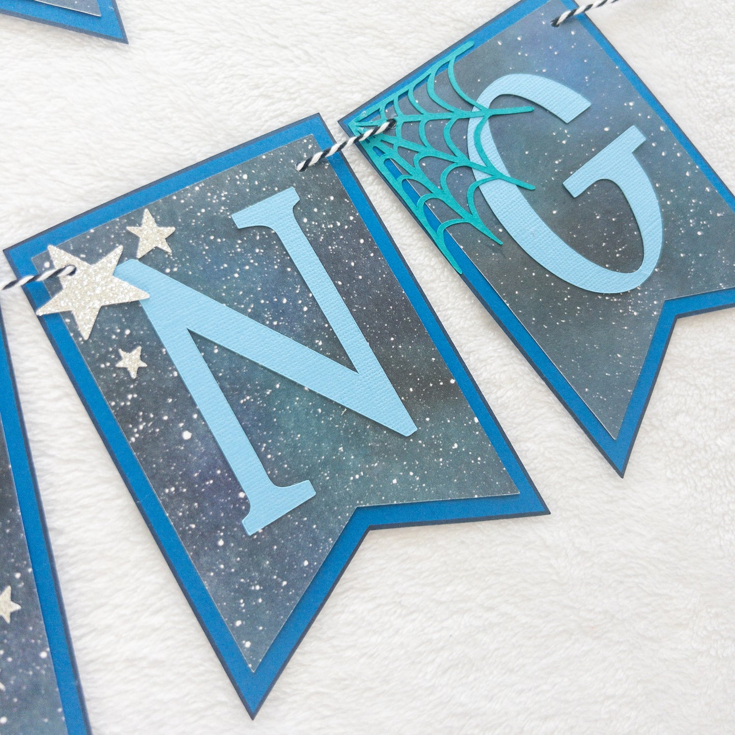 A banner with blue paper letters spelling 'A BABY IS BREWING' with stars and a blue border