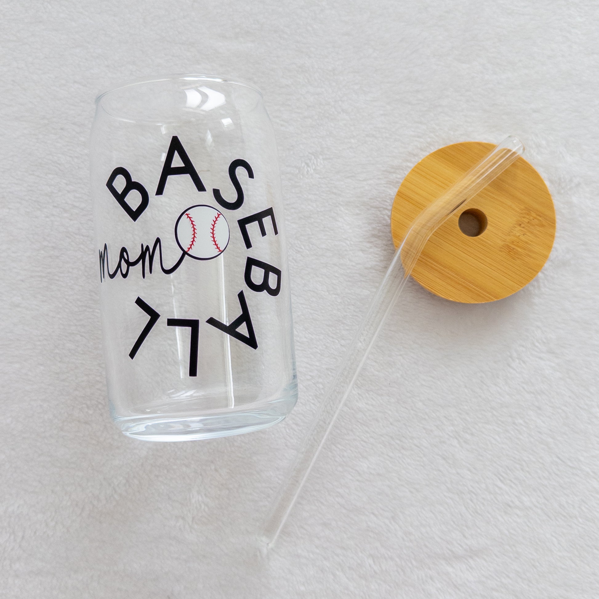 A clear glass cup with a 'Baseball Mom' text and a baseball symbol printed on it, including a straw and a lid.